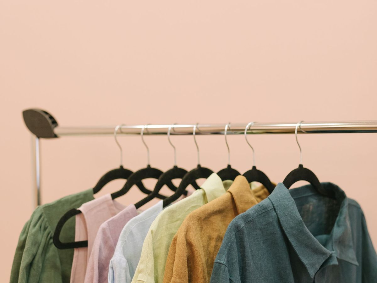 A rail of shirts in muted colours hanging on wooden and black hangers