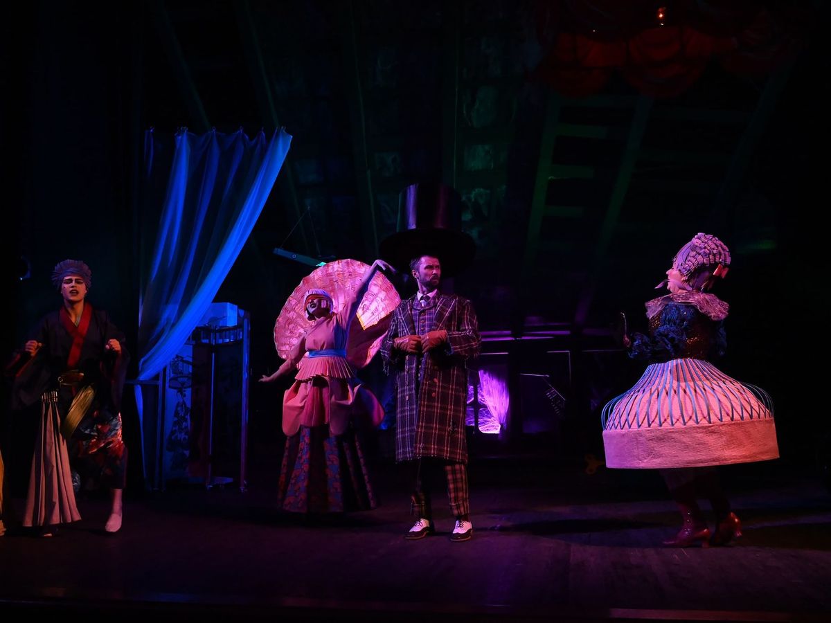 Performers in brightly coloured costumes on a stage under theatrical lighting