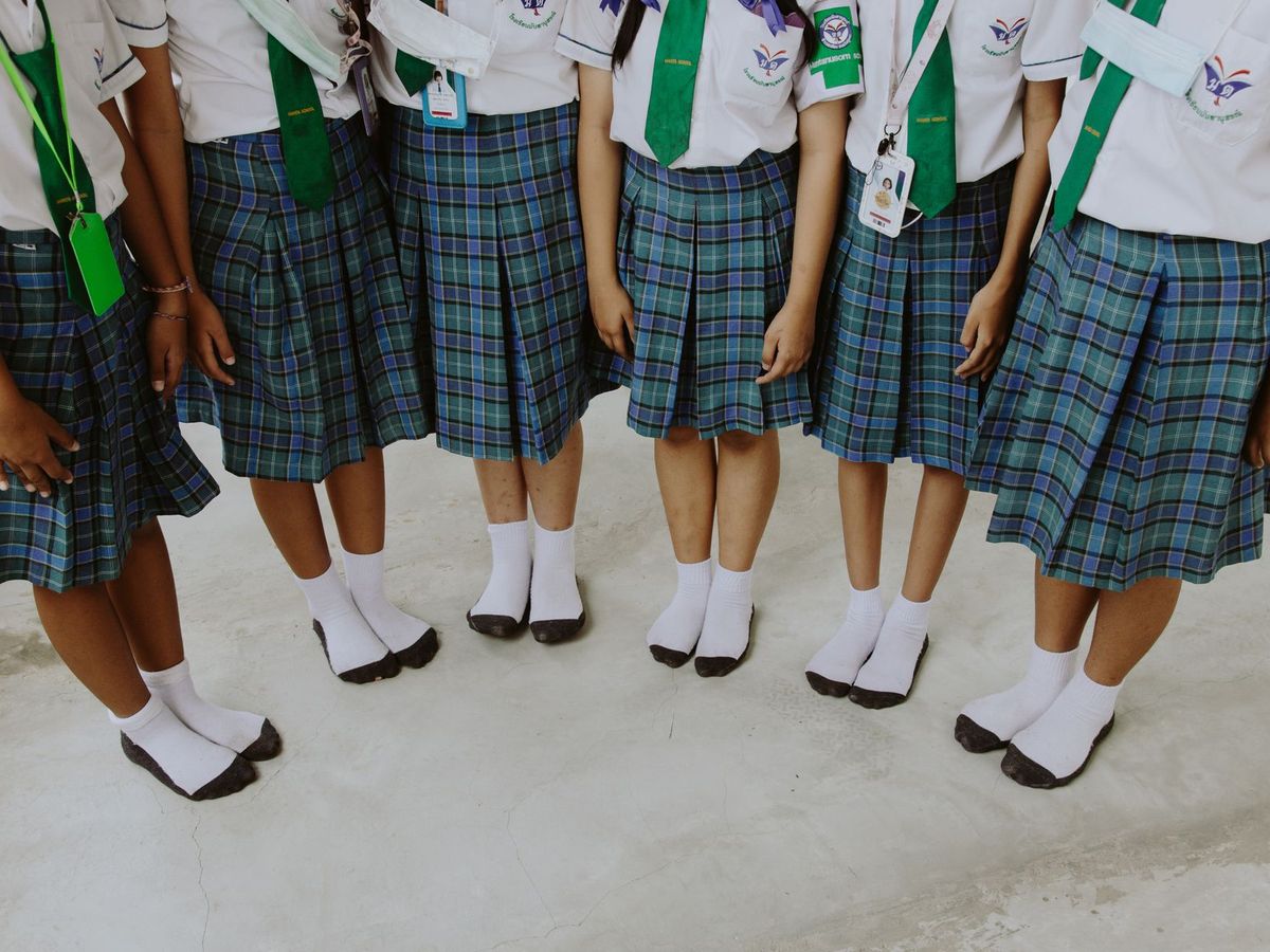 A row of pupils in tartan school uniform skirts and white shirts, photographed from above